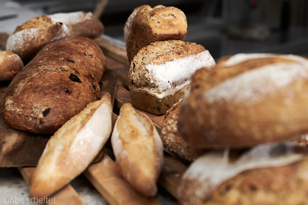 Brote, die nicht verkauft wurden, kann man immerhin zu Paniermehl weiterverarbeiten. Verschiedene Brote liegen auf einer hölzernen Unterlage.